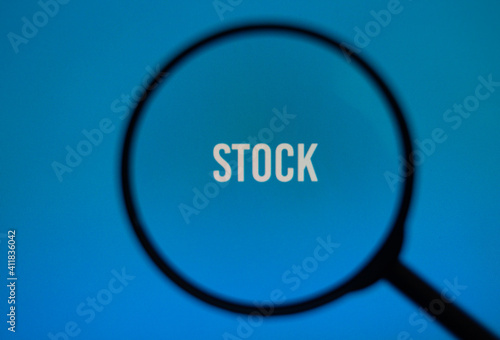 Word stock on blue screen through magnifying glass.