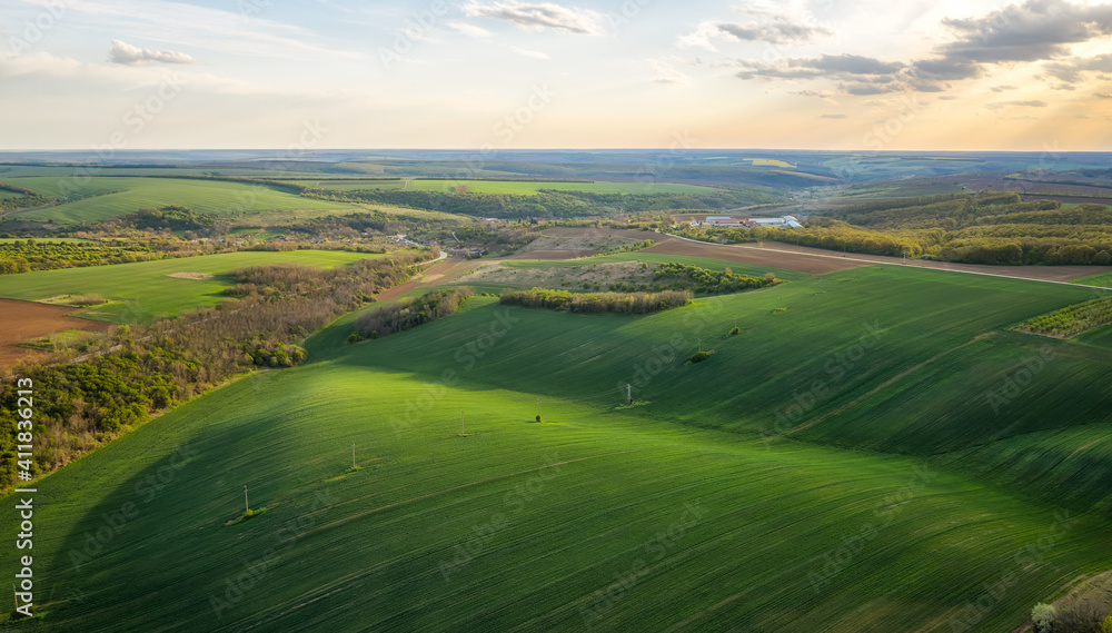 Aerial view of beautiful countryside with green rolling field in golden hour before sunset.. Aerial view of beautiful countryside with green rolling field in golden hour before sunset..