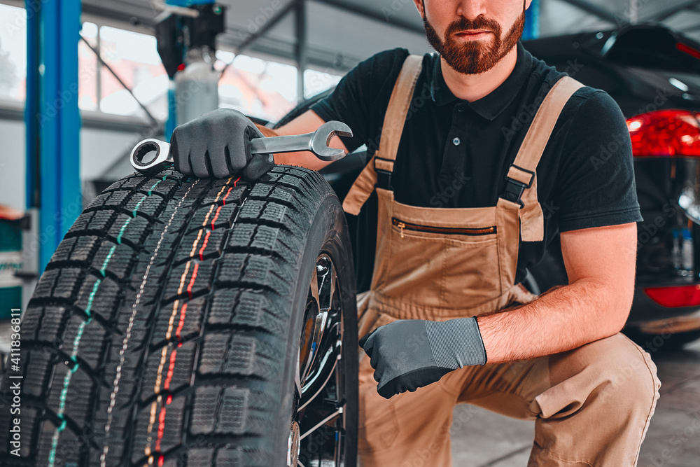 Mechanic holding car tire at garage. Mechanic holding car tire at garage.
