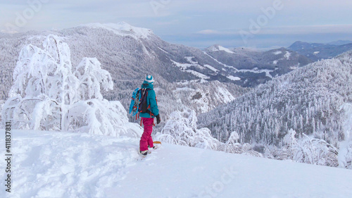 CLOSE UP: Woman observes the stunning winter landscape before snowboarding.