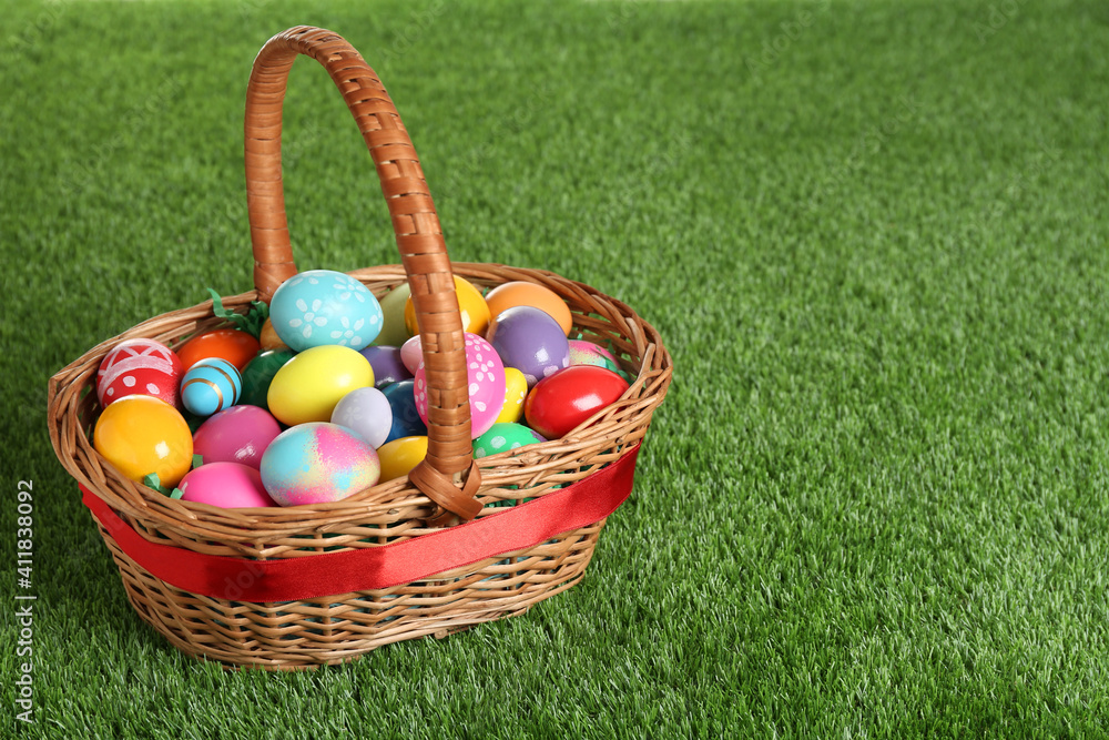 Wicker basket with Easter eggs on green grass. Space for text Wicker basket with Easter eggs on green grass. Space for text