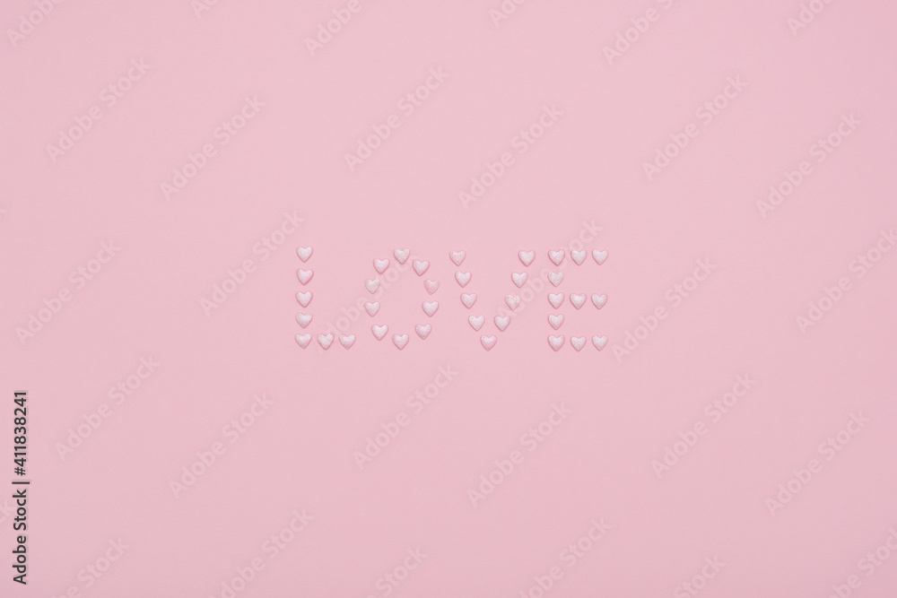 Word love made of shiny pearly candy hearts on a pale pink background