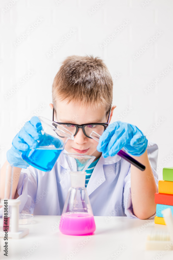A schoolboy studies multi-colored substances in test tubes, conducts experiments - a portrait on a white background. Concept for the study of coronavirus in the laboratory A schoolboy studies multi-colored substances in test tubes, conducts experiments - a portrait on a white background. Concept for the study of coronavirus in the laboratory