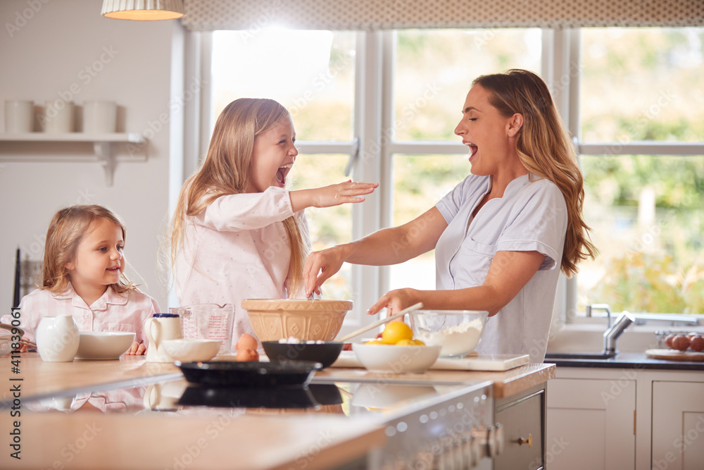Mother And Two Daughters Making Pancakes In Kitchen At Home Together Mother And Two Daughters Making Pancakes In Kitchen At Home Together