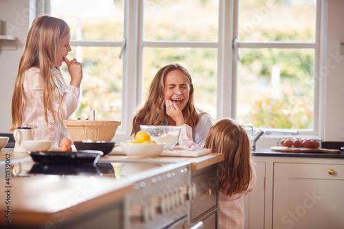 Mother And Two Daughters Making Messy Pancakes In Kitchen At Home Together