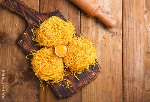 Tagliatelle pasta is thin. Traditional Italian named Angel Hair. Italian egg pasta, homemade and fresh on a wooden table. Rustic cuisine of the north of Italy.  Copy space . Above photo