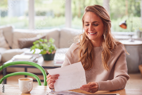 Foto Woman With Digital Tablet Sitting At Table At Home Reviewing Domestic Finances
