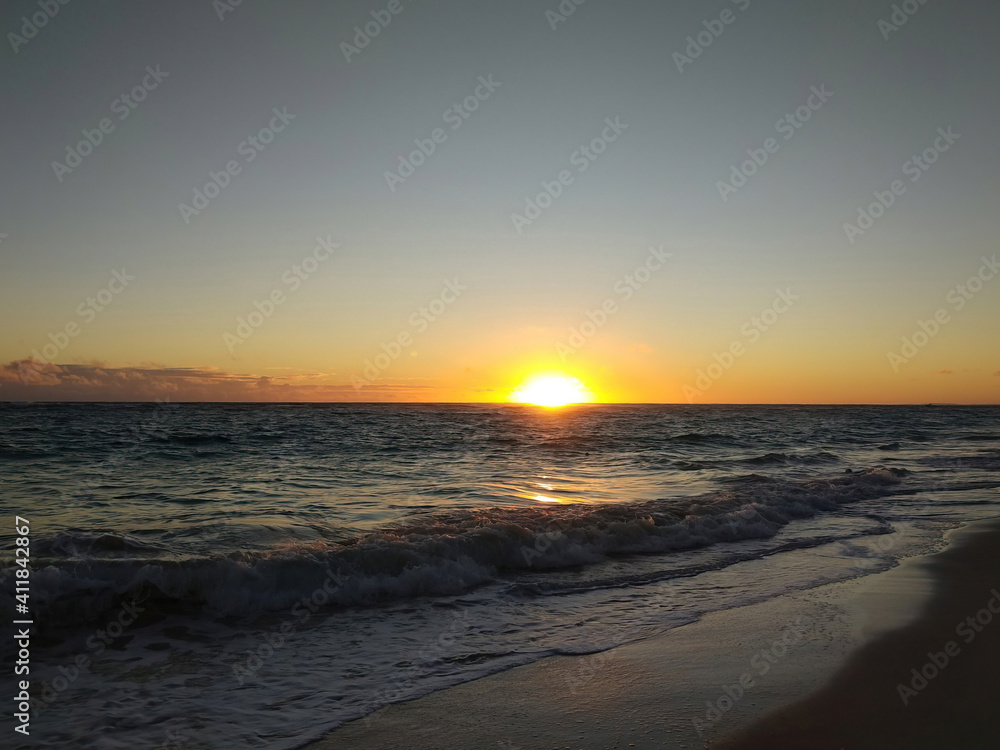 Sun goes down at the tropical beach. Waves come to a sand. Dusk twilight time of summer season at a resort vacation area