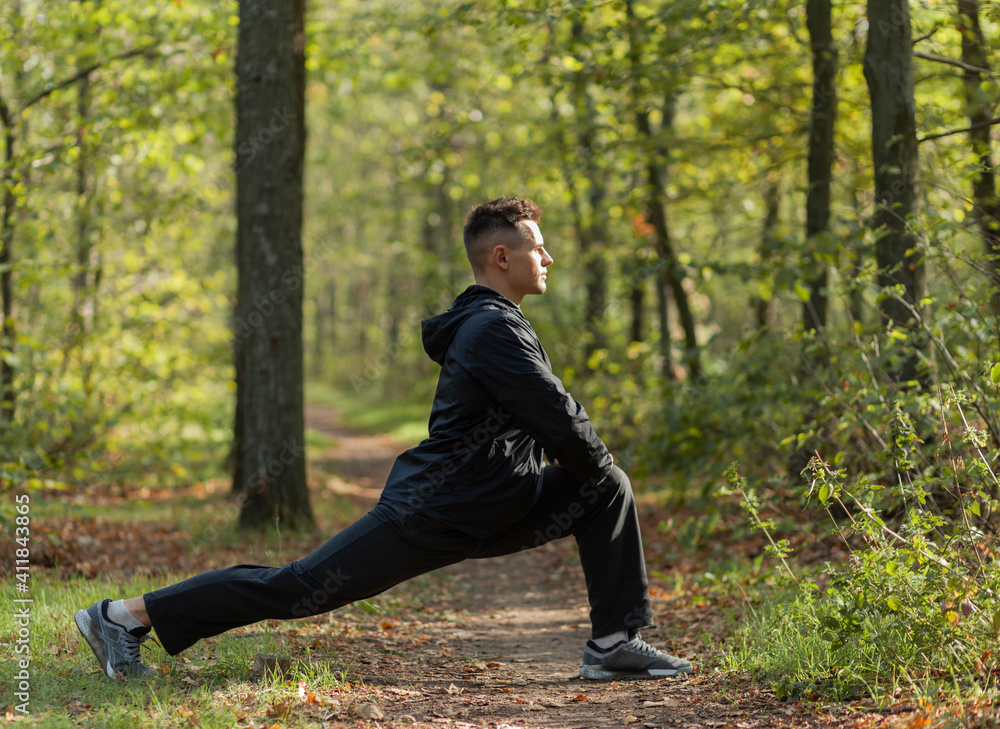 Active sport man trains warm-up exercises or stretching in the autumn forest. Healthy lifestyle. Outdoor workout Active sport man trains warm-up exercises or stretching in the autumn forest. Healthy lifestyle. Outdoor workout