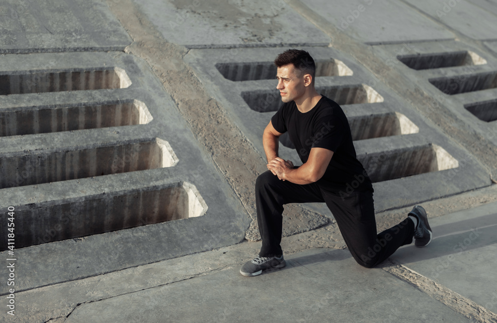 Active muscular man exercising outdoors on concrete slabs. Healthy lifestyle concept Active muscular man exercising outdoors on concrete slabs. Healthy lifestyle concept