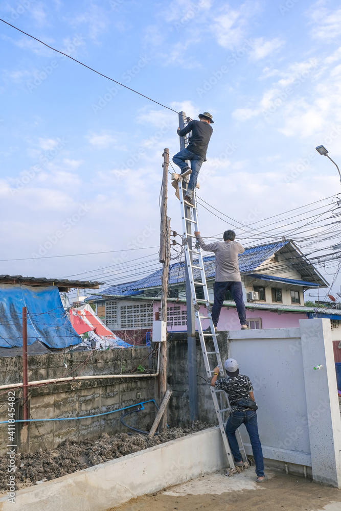 Electrician male Team climbing pole for install wire power cable . professional technician worker setting connect electric metal box