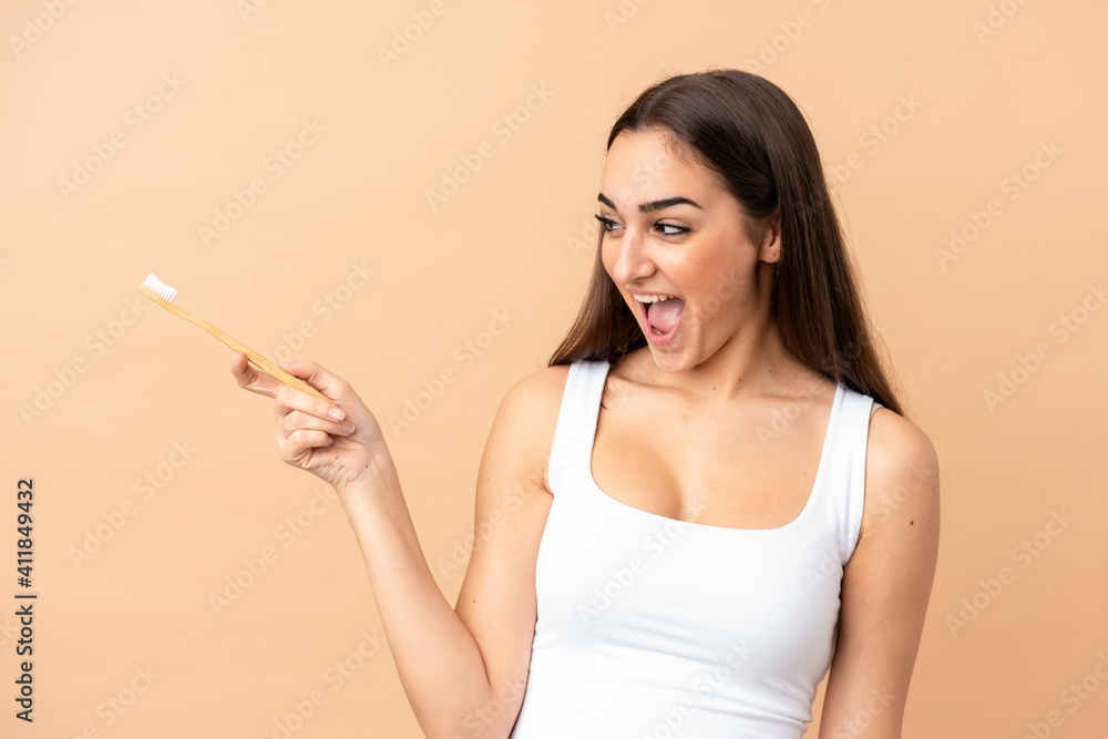 Young caucasian woman isolated on beige background with a toothbrush and surprised expression Young caucasian woman isolated on beige background with a toothbrush and surprised expression