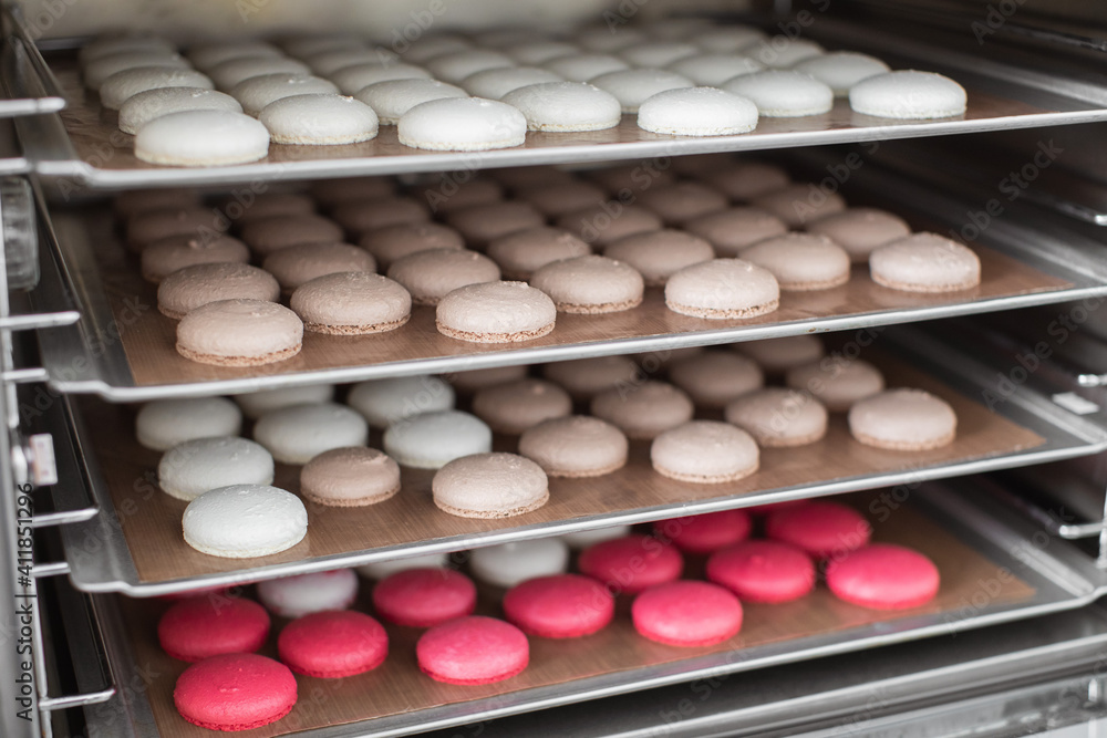 Desserts, sweets, luxury cookies macarons. Close up horizontal shot of four baking trays with colorful macaroon shells in the oven after baking. Macarons manufacturing process Desserts, sweets, luxury cookies macarons. Close up horizontal shot of four baking trays with colorful macaroon shells in the oven after baking. Macarons manufacturing process