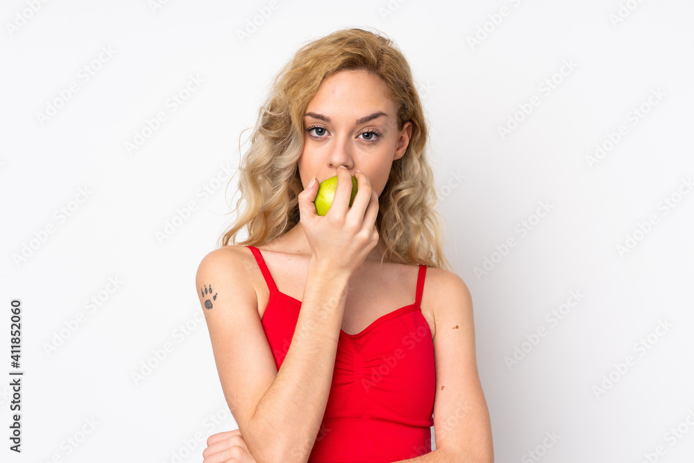Young blonde woman isolated on white background eating an apple Young blonde woman isolated on white background eating an apple