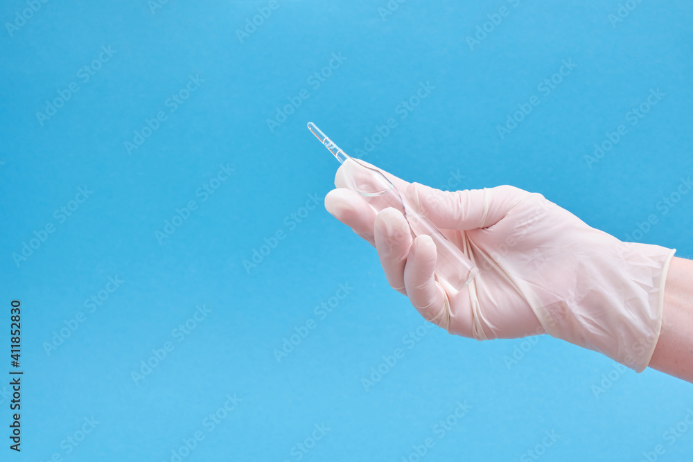 Ampoule with a medicine or vaccine and a syringe in hands in rubber gloves on a blue background Ampoule with a medicine or vaccine and a syringe in hands in rubber gloves on a blue background