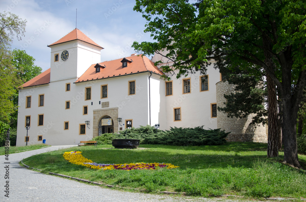 	
Castle in Moravský Kras, Czech Republic, White building with red roof, green grass with flower bed, tree, path