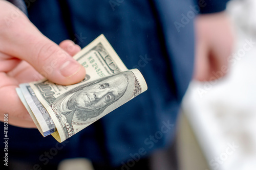 the hand holds out several hundred dollar bills folded in half