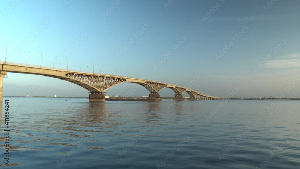 The boat goes straight across the bridge on a calm river and sails into the sunset The boat goes straight across the bridge on a calm river and sails into the sunset
