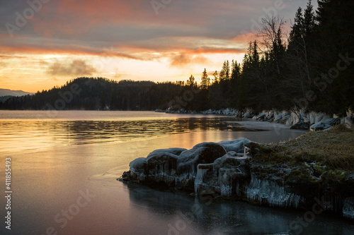 Icy frozen shore of the lake in sunset time.