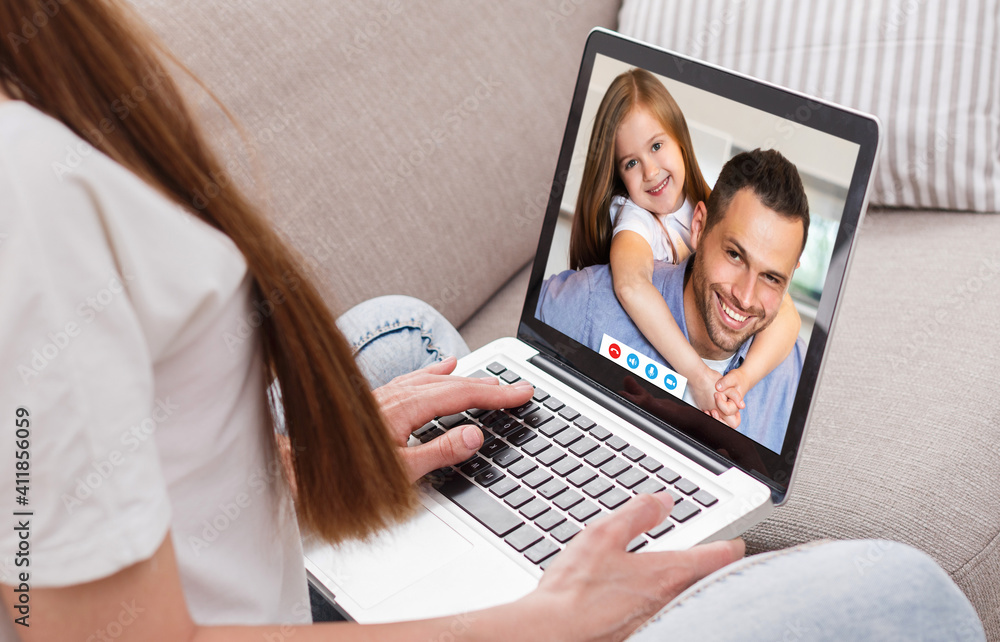 Distance communication. Millennial woman using laptop to talk to her husband and daughter online from home Distance communication. Millennial woman using laptop to talk to her husband and daughter online from home