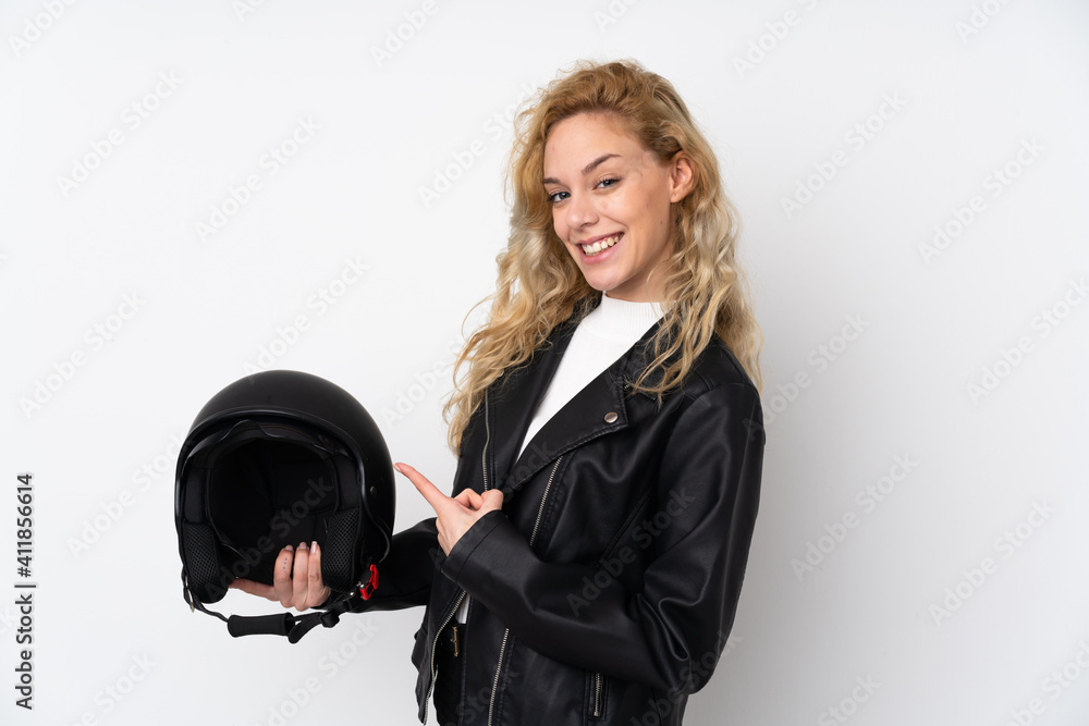 Young blonde woman with a motorcycle helmet isolated on white background and pointing it Young blonde woman with a motorcycle helmet isolated on white background and pointing it