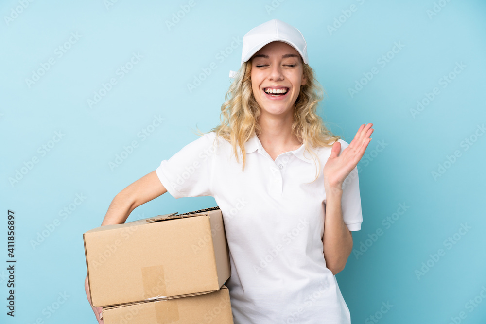 Young delivery woman isolated on blue background laughing Young delivery woman isolated on blue background laughing