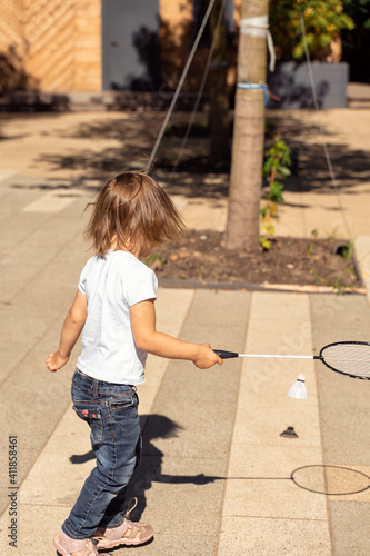 playful kid in a white t-shirt plays bambinton in the park on a summer sunny day photo