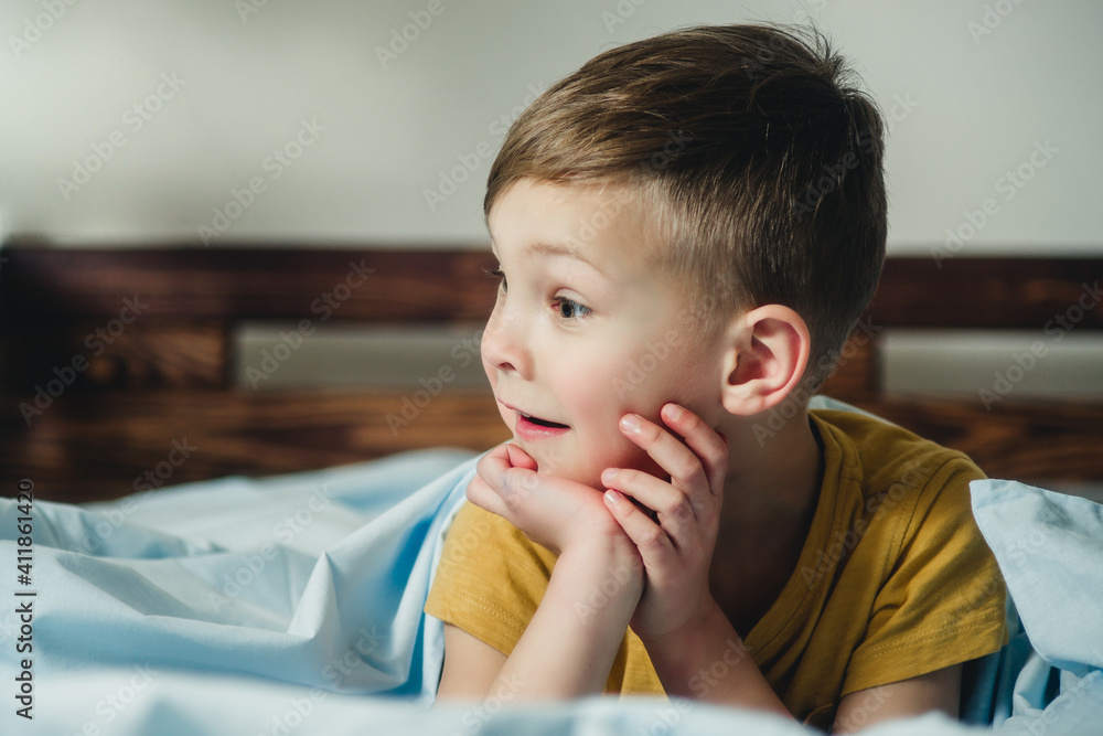 cheerful and surprised child lies on the bed cheerful and surprised child lies on the bed