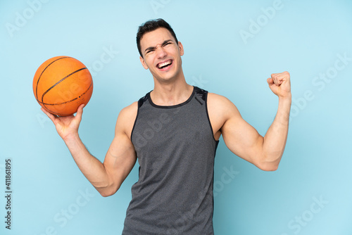 Man on isolated blue background playing basketball