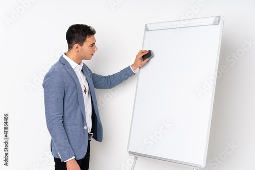 Young caucasian handsome man isolated on purple background giving a presentation on white board © luismolinero