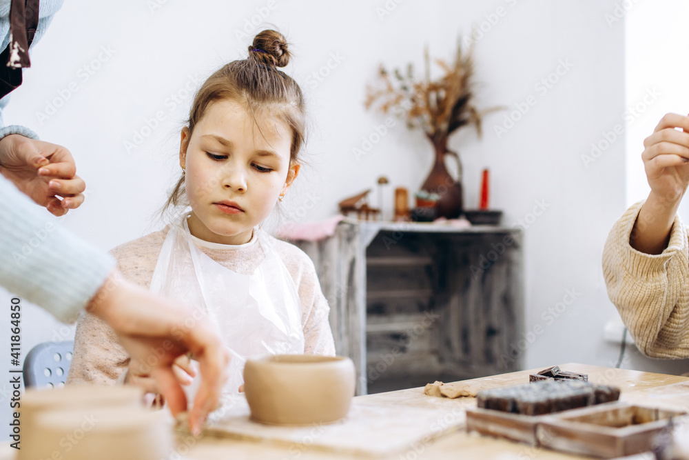 Mother and daughter decorate a clay plate before firing in a pottery studio, decorate a plate with lavender branches Mother and daughter decorate a clay plate before firing in a pottery studio, decorate a plate with lavender branches