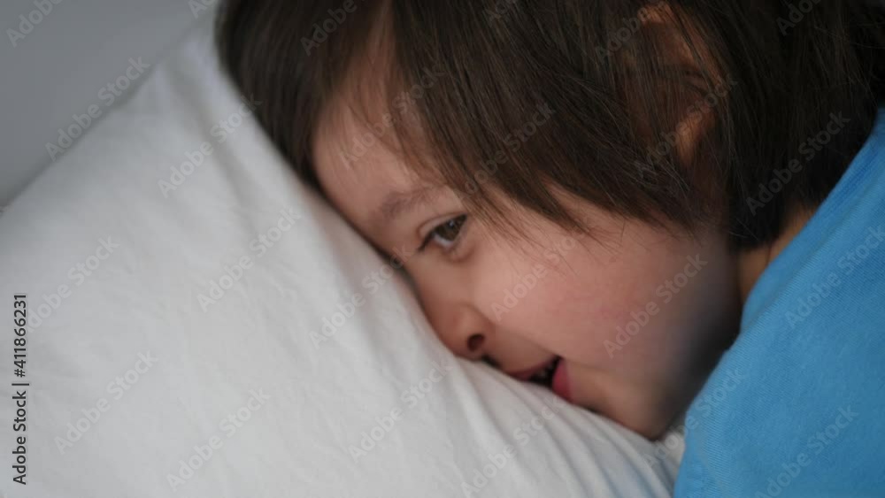 boy child in a blue t-shirt lies on a white bed and falls asleep boy child in a blue t-shirt lies on a white bed and falls asleep