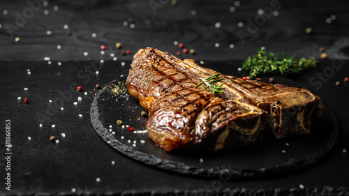 Grilled T-bone or aged wagyu porterhouse grilled beef steak on stone table. Long banner format, top view