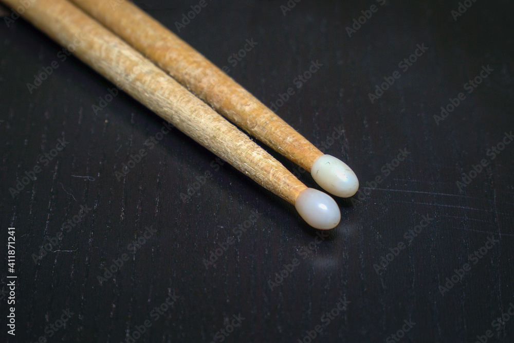Used wooden drumsticks with white tips on dark background Used wooden drumsticks with white tips on dark background