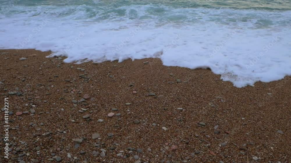 Beautiful white waves in blue sea. Beach sand with stones. Summer sunset seascape. Water texture. Montenegro, Balkans, Southern Europe. Slow motion Beautiful white waves in blue sea. Beach sand with stones. Summer sunset seascape. Water texture. Montenegro, Balkans, Southern Europe. Slow motion