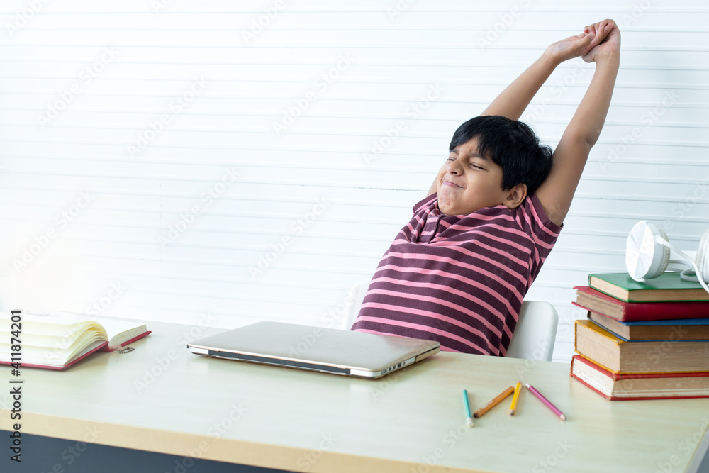 Indian student boy get tiring and bored from online study at home, stretching hands after finish his online learning, New normal lifestyle Indian student boy get tiring and bored from online study at home, stretching hands after finish his online learning, New normal lifestyle