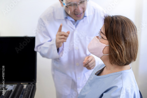Optometrist man checking senior Asian woman patient vision  Asian senior woman wearing protection mask