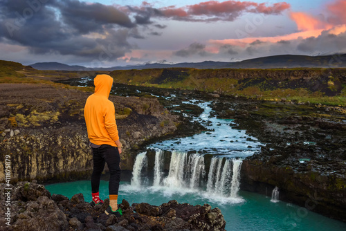 Hiker standing at the edge of the Thjofafoss waterfall in Iceland photo