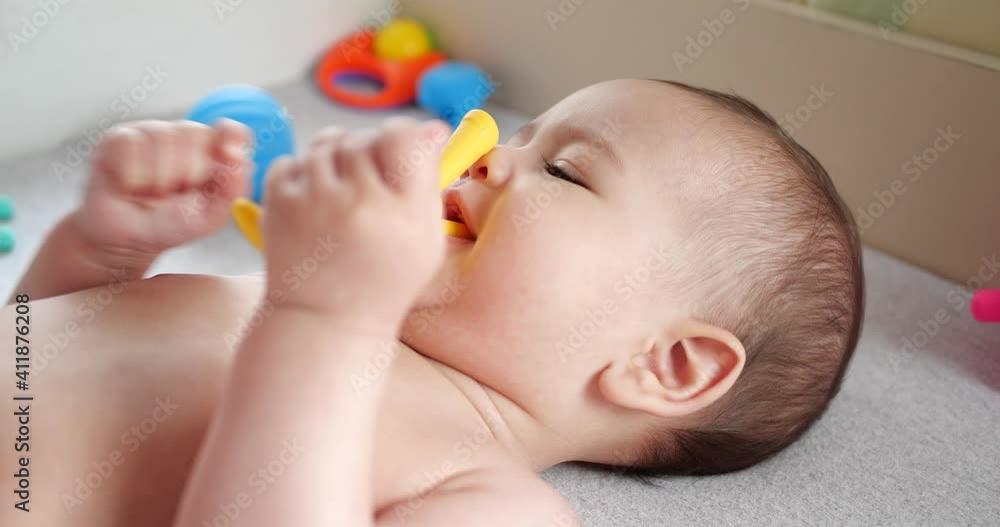 infant, childhood concept - close-up of smiling happy Baby plays with a teether. Teeth cutting. First teeth. Joy toothless 7 months baby bite, gnaws teether toy infant, childhood concept - close-up of smiling happy Baby plays with a teether. Teeth cutting. First teeth. Joy toothless 7 months baby bite, gnaws teether toy