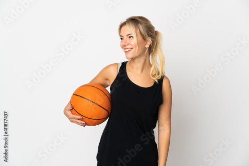 Young Russian woman playing basketball isolated on white background looking side