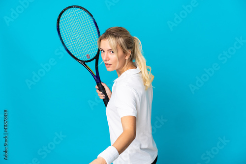 Young Russian woman isolated on blue background playing tennis