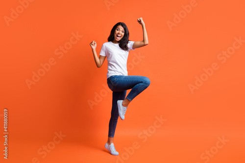 Full length photo of crazy girl open mouth rejoice wear white t-shirt jeans footwear isolated orange color background © deagreez