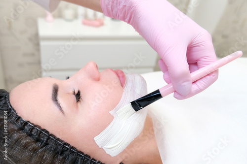 cosmetology. Close up picture of lovely young woman with closed eyes receiving facial cleansing procedure