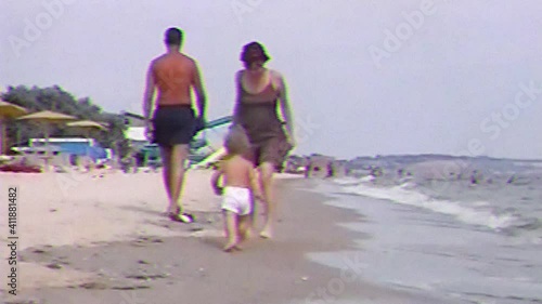 VHS footage from little happy boy run along the sand beach and smiling. Old home family movie of cute baby with mother playing and enjoying on sea beach.