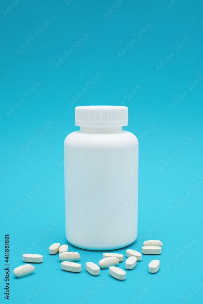 White bottle with pills isolated on blue background. White bottle with pills isolated on blue background.