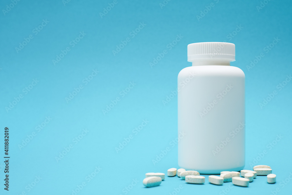 White bottle with pills isolated on blue background. White bottle with pills isolated on blue background.