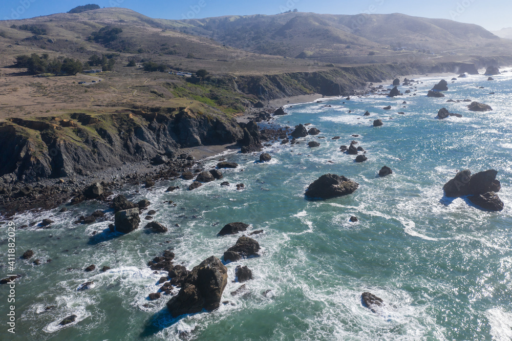 Fototapeta premium The Pacific Ocean washes against the rugged shoreline of northern California on a beautiful winter day. The scenic Pacific Coast Highway runs along much of the edge of California.