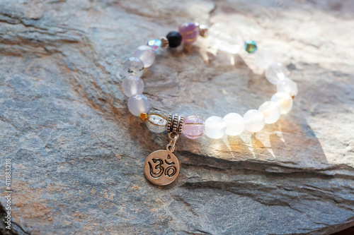 Silver pendant sanskrit om mineral beads bracelet on neutral natural rocky background