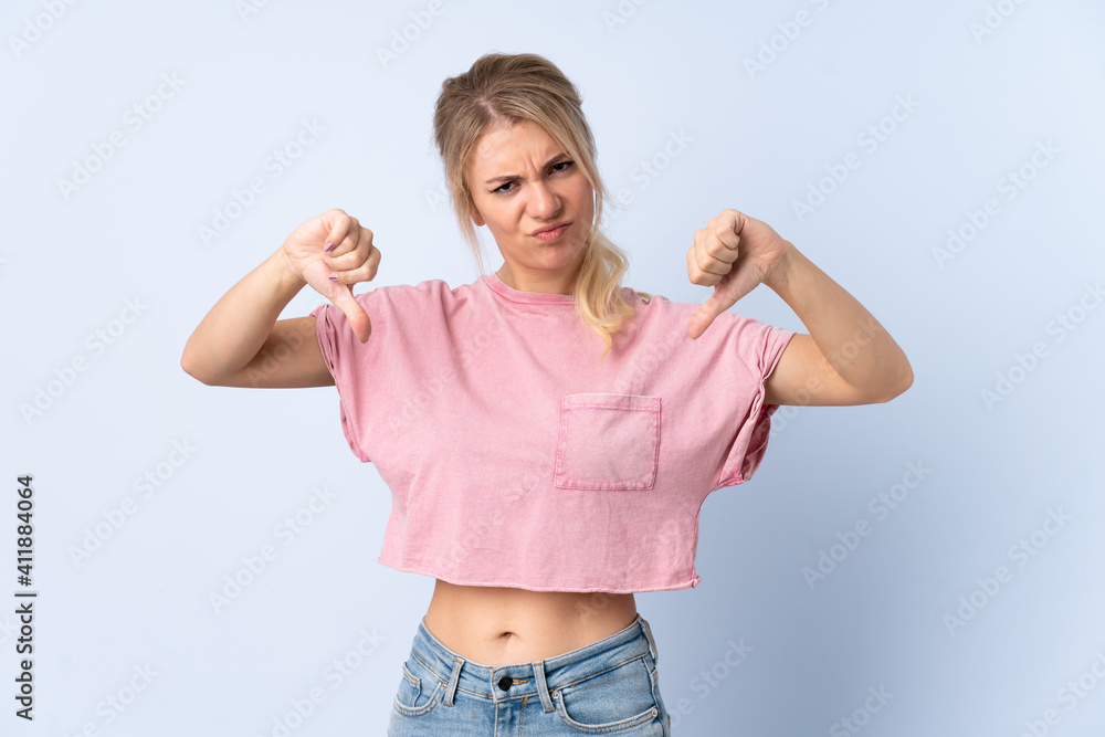 Blonde woman over isolated blue background showing thumb down with two hands Blonde woman over isolated blue background showing thumb down with two hands