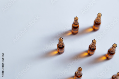 Brown ampoule with medicine on a gray background.Skincare products.Ampoules with vitamin C.Beauty industry.Coronavirus vaccination. © Olha